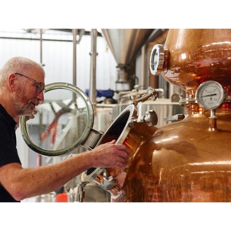 Distillery owner Wayne looking inside a copper still